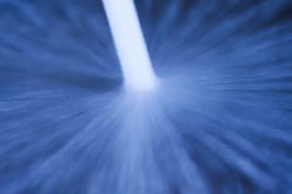 A close-up of a white rod stirring water, creating radial patterns and motion blur in a blue-tinted scene, reminiscent of the powerful cleaning action seen in professional Hydro Jetting Service.